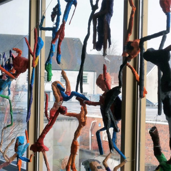 Colourful decorated wire figures displayed in a school on the window
