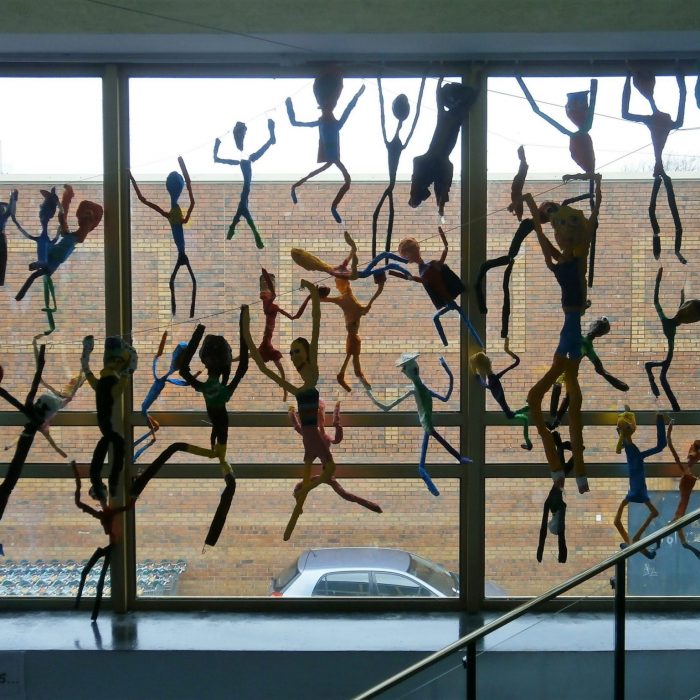Colourful decorated wire figures displayed in a school on the window