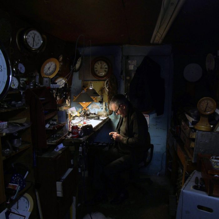 Photo of a dimly lit room of a watchmaker working by Irish Artist David O'Rourke